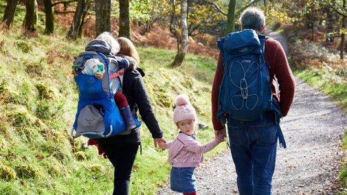 A family walks through the oak woodland in Borrowdale on a sunny autumn day